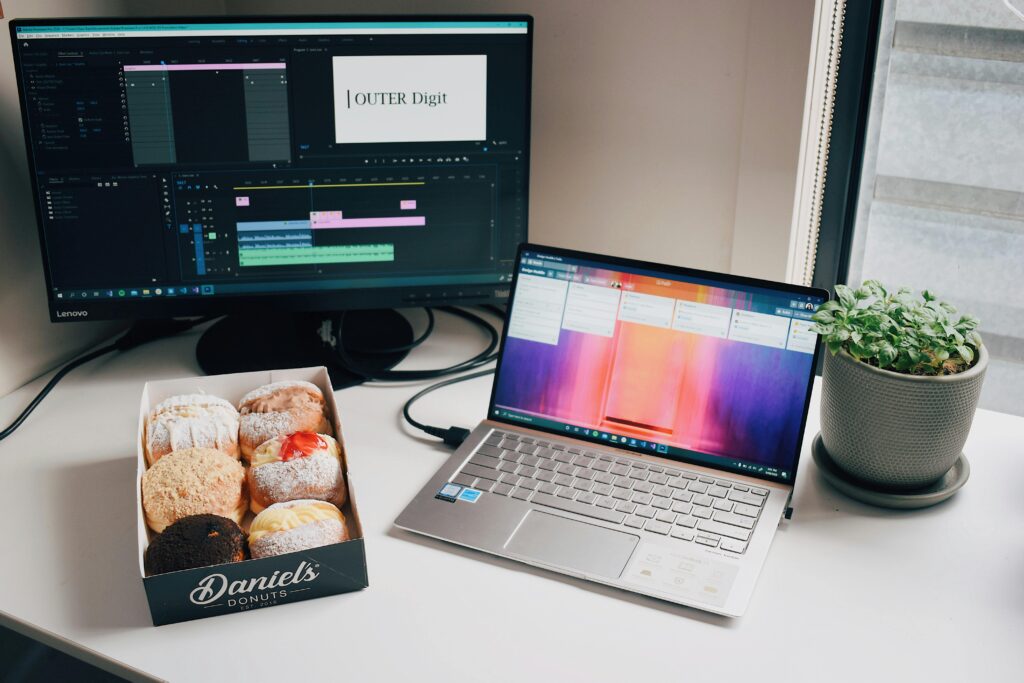 laptop and monitor video editing with some donuts on the side for relaxing